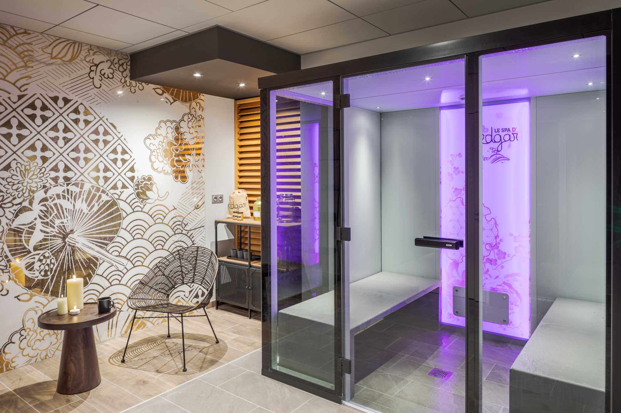 Vue de l’espace détente de l’hôtel Le Edgar avec sauna équipé de spots lumineux à couleurs variables.