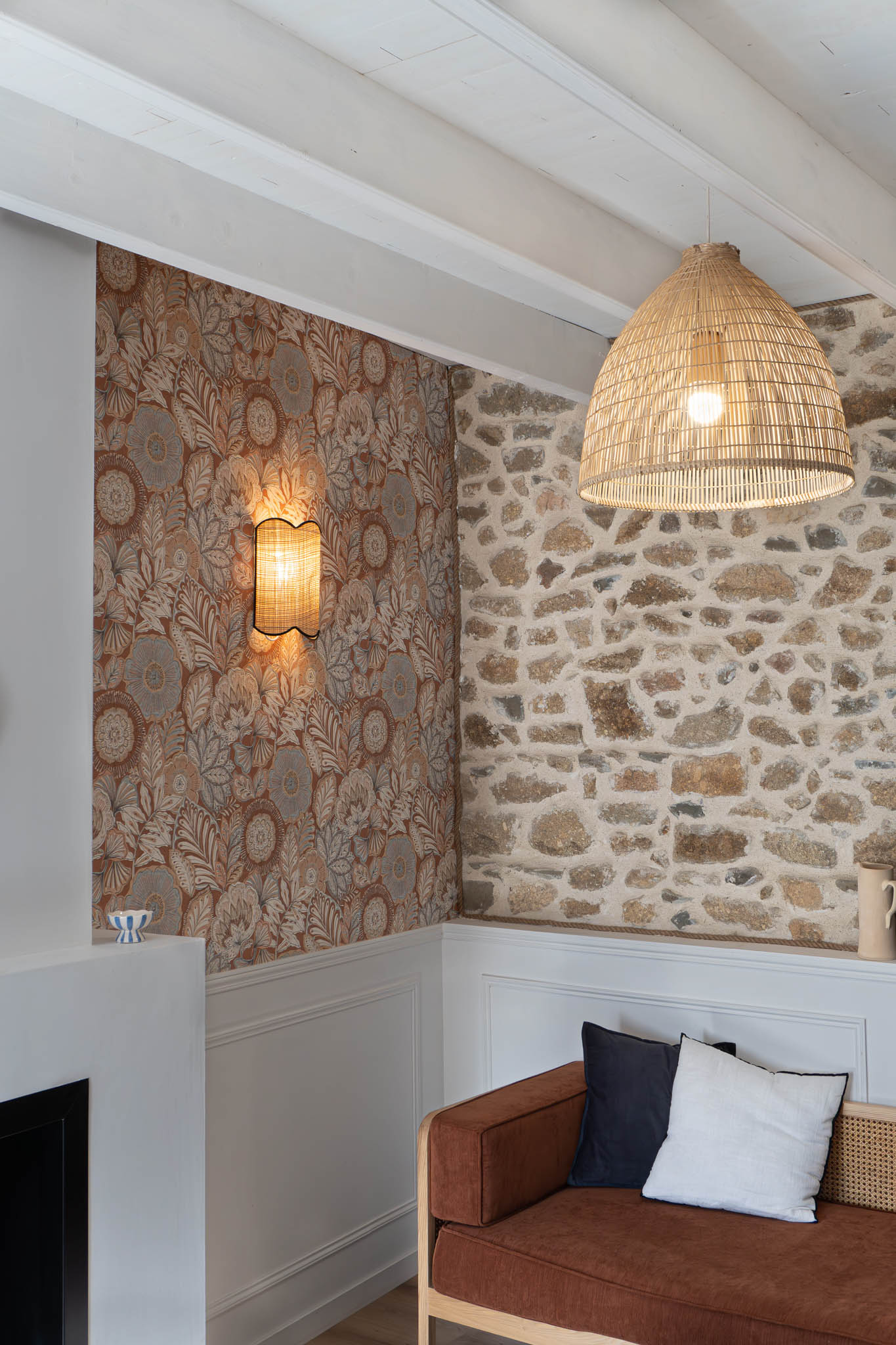 Vue du salon mettant en scène les éclairages, les murs en pierre naturelle et une tapisserie graphique.